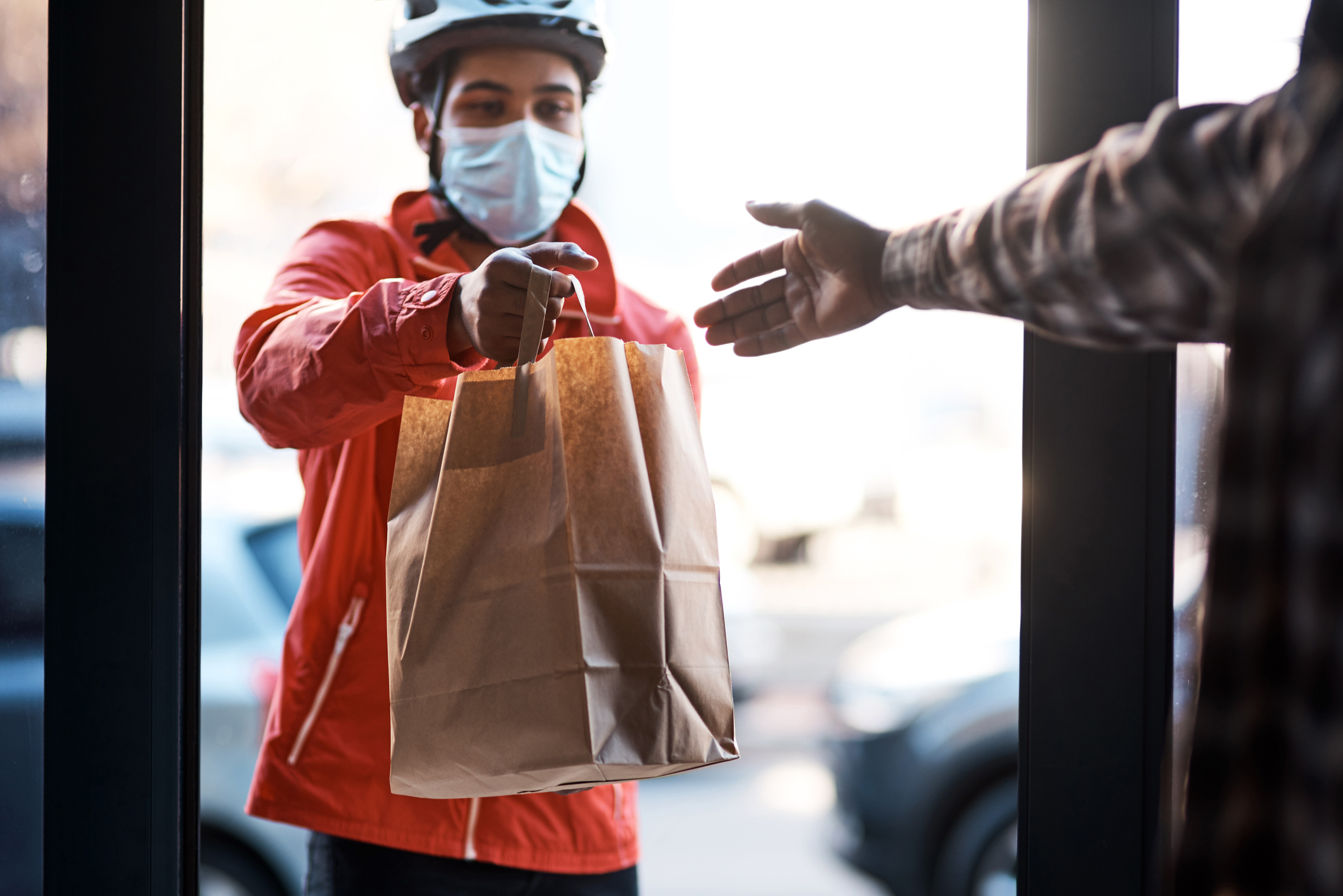 Shot of a masked man delivering a food package