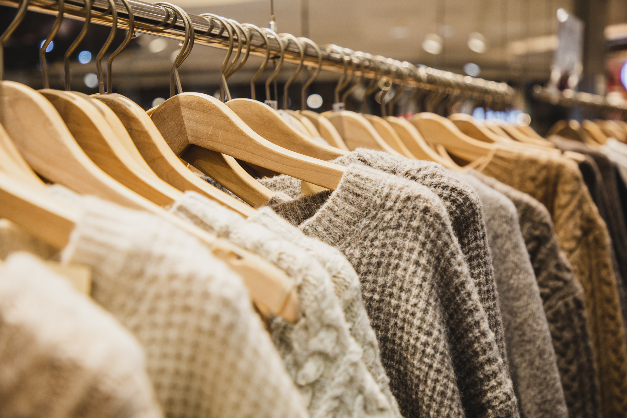 knit sweaters hanging on clothes rack in a store