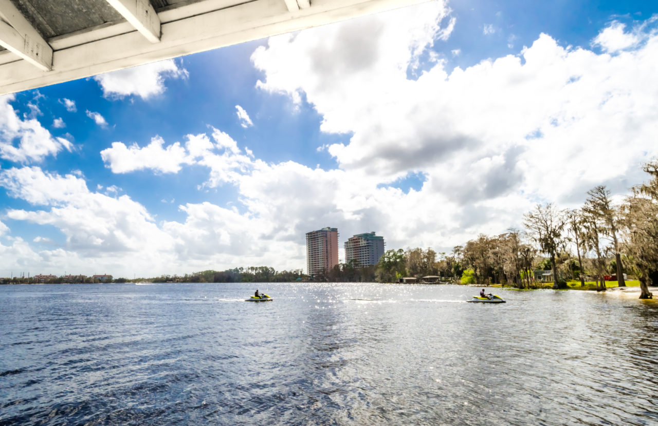 People ride jet skis on Lake Buena vista  in Orlando Florida with city skyline behind and scenic lake views. Orlando’s only beach is also a water sport hotspot