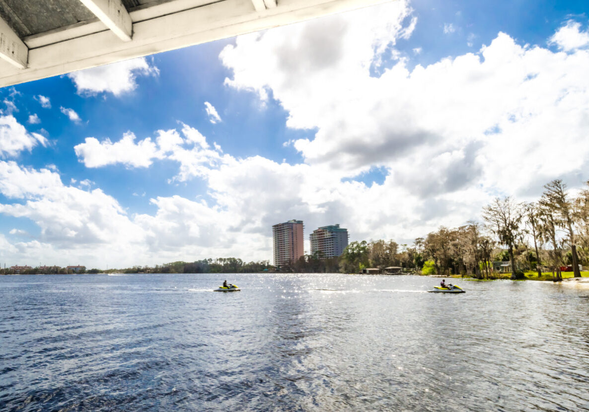 People ride jet skis on Lake Buena vista  in Orlando Florida with city skyline behind and scenic lake views. Orlando’s only beach is also a water sport hotspot