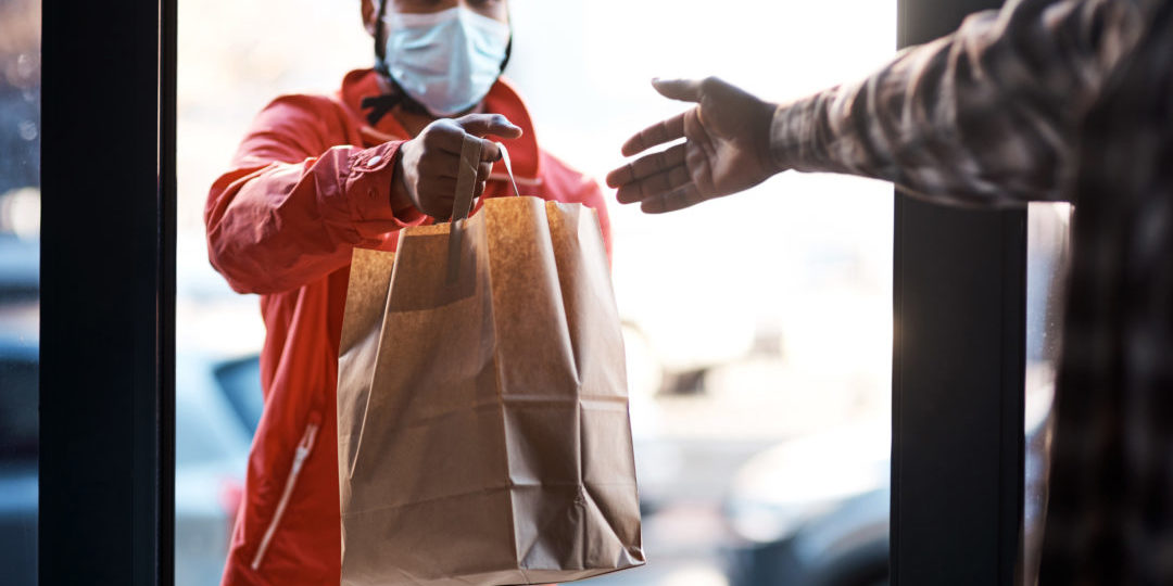 Shot of a masked man delivering a food package