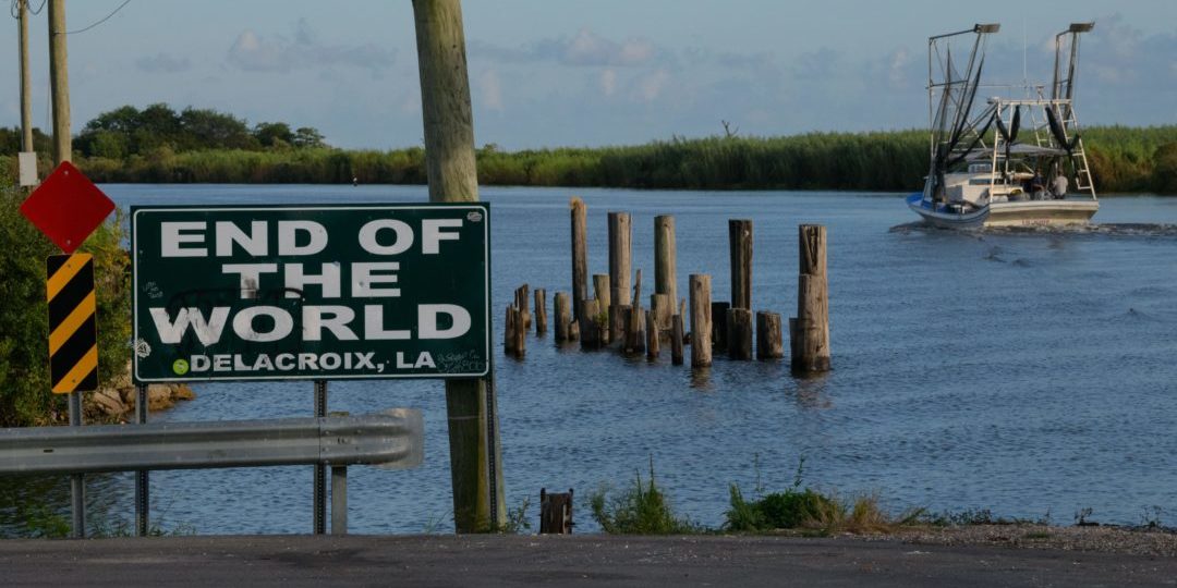 A sign for the End of the World Marina, that was destroyed by Hurricane Katrina, is seen in Delacroix, La. Tuesday, Oct. 15, 2019 as shrimp boat passes. Delacroix was settled by Islenos from the Canary Islands who spoke Spanish and near and interacted with Filipino settlers at the nearby St. Malo platform on Lake Borgne in 1800s. Photo by Matthew Hinton