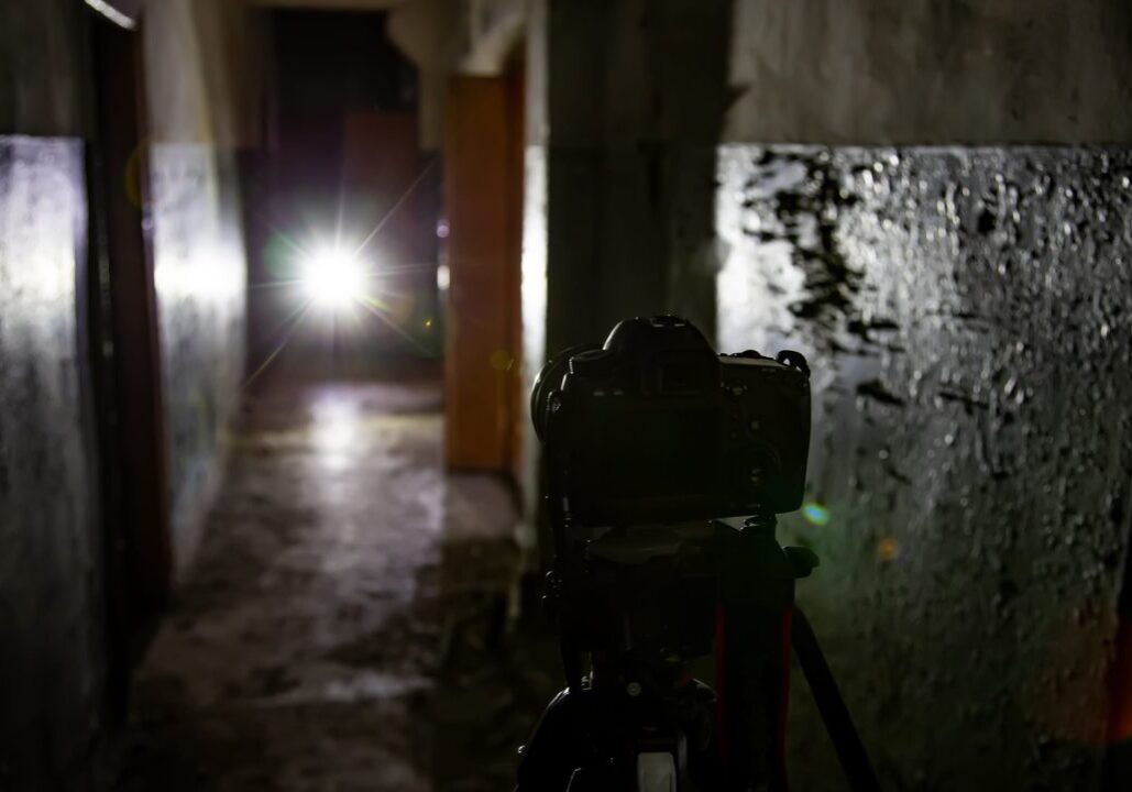 Camera on tripod in dark abandoned building. Urban exploration concept.