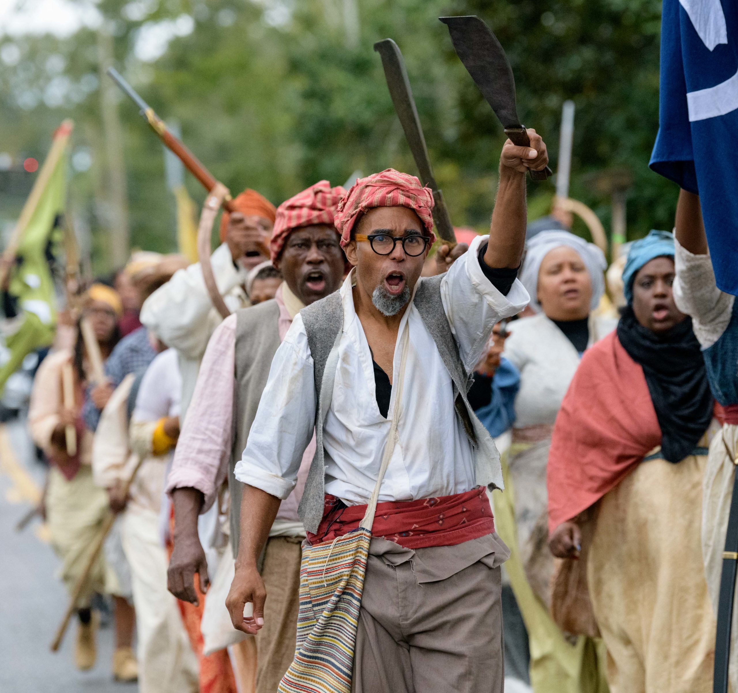 Lead by artist Dread Scott, wearing red sash, a group of re-enactors recreate the largest slave revolt in United States history, the German Coast Uprising of 1811 in LaPlace, Louisiana, Friday, Nov. 8, 2019 with shouts of “On to New Orleans! Freedom or Death!” In 1811 Charles Deslondes led a group who attacked slave owner Manual Andry at his plantation, which still stands and is called Woodland Plantation now. John McCusker recreated Andry and was attacked at the plantation while another plantation owner recreated an attack on the Mississippi River levee in LaPlace. The rebellion got as far as modern-day Kenner, Louisiana before troops from New Orleans forced the 500 slaves back and captured many of them. Over 50 of the rebels were sentenced to death and beheaded with their heads place on pikes along the river levee while others were placed in the French Quarter in New Orleans. Dread Scott didn’t learn of the slave rebellion until recently as the rebellion is mostly unknown even to residents of St. John Parish, but Scott feels it’s important for people to know that many slaves were not passive and fought for their freedom throughout history. Photo by Matthew Hinton