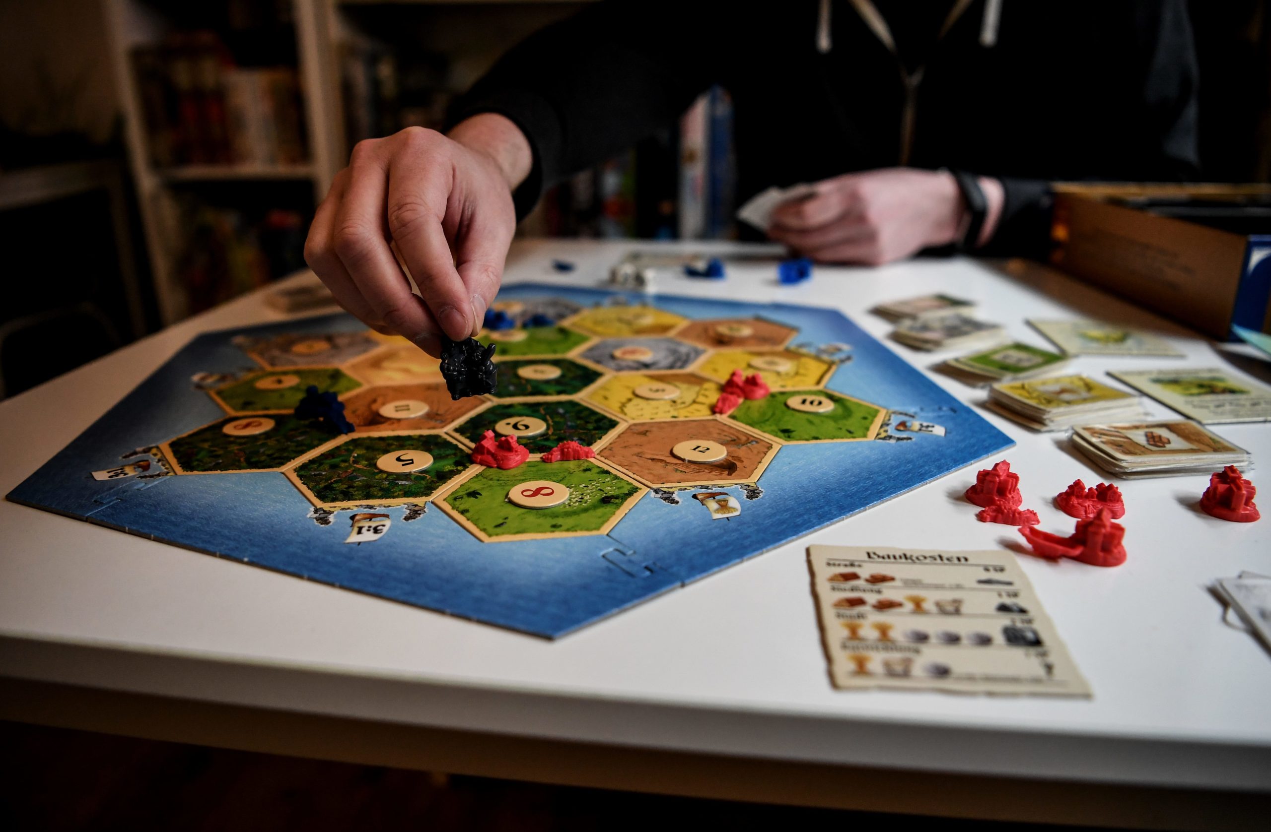 30 April 2020, Berlin: Tim Overkamp shows the game "Settlers of Catan" in the Ludothek "Spielwiese". In the "Spielwiese" he and his team lend out about 1500 games. To dpa-korr "Game lenders: Don't let the fun of the game be spoiled". Photo: Britta Pedersen/dpa-Zentralbild/ZB (Photo by Britta Pedersen/picture alliance via Getty Images)