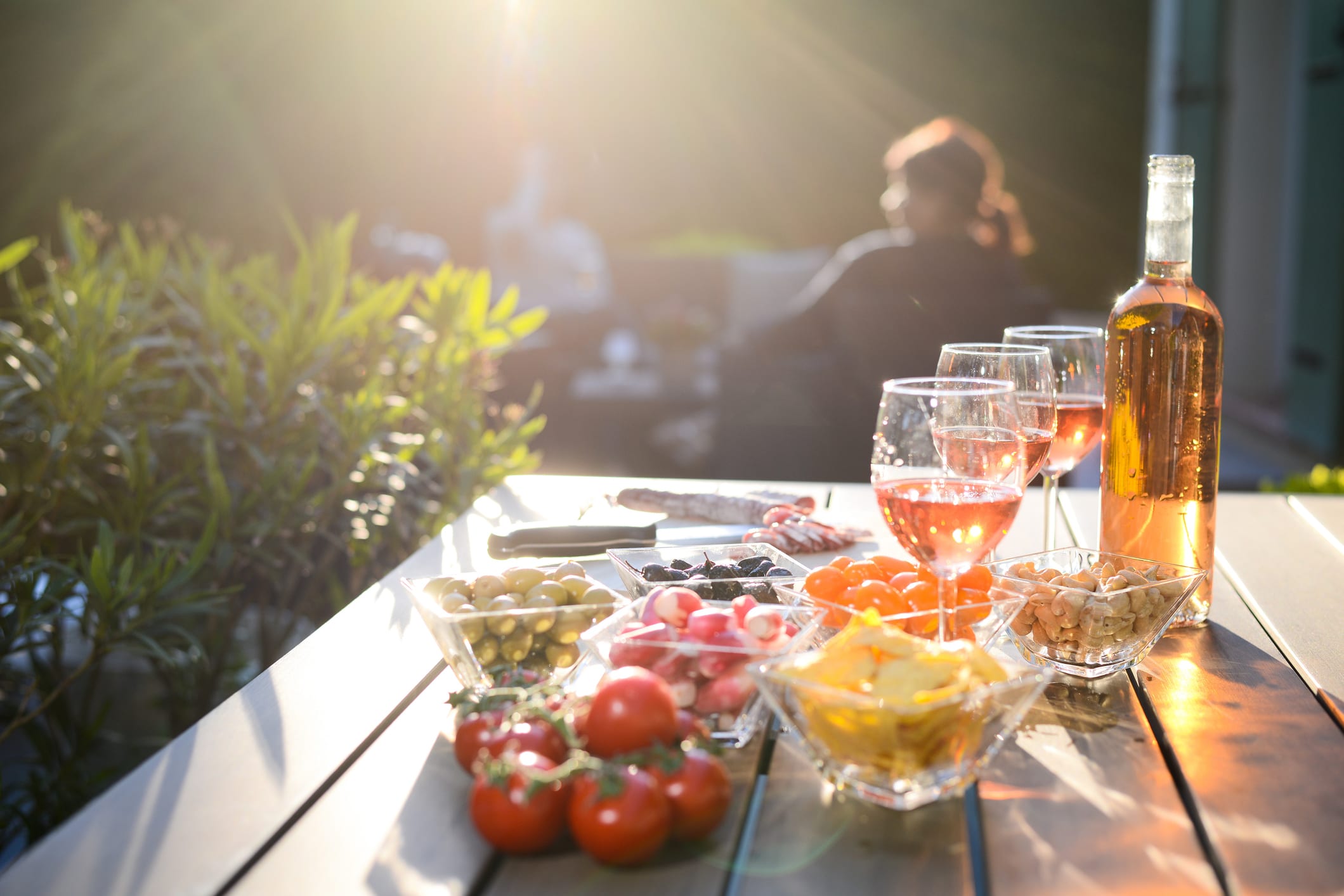 Holiday summer brunch party table outdoor in house backyard with appetizer, glass of rose wine, fresh drink and organic vegetables.