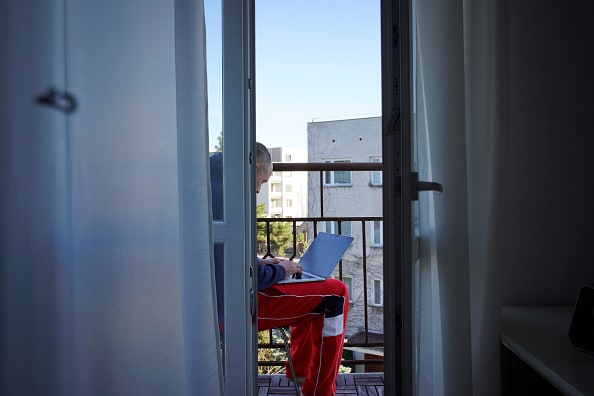 A man is seen working from home on his balcony in Warsaw, Poland on April 5, 2020. Despite rising tempertures the government has urged people to stay and respect distancing rules to prevent the spread of the coronavirus. Poland has seen it's largest increase in active cases with 475 newly infected people tested on Sunday. (Photo by Jaap Arriens/NurPhoto via Getty Images)