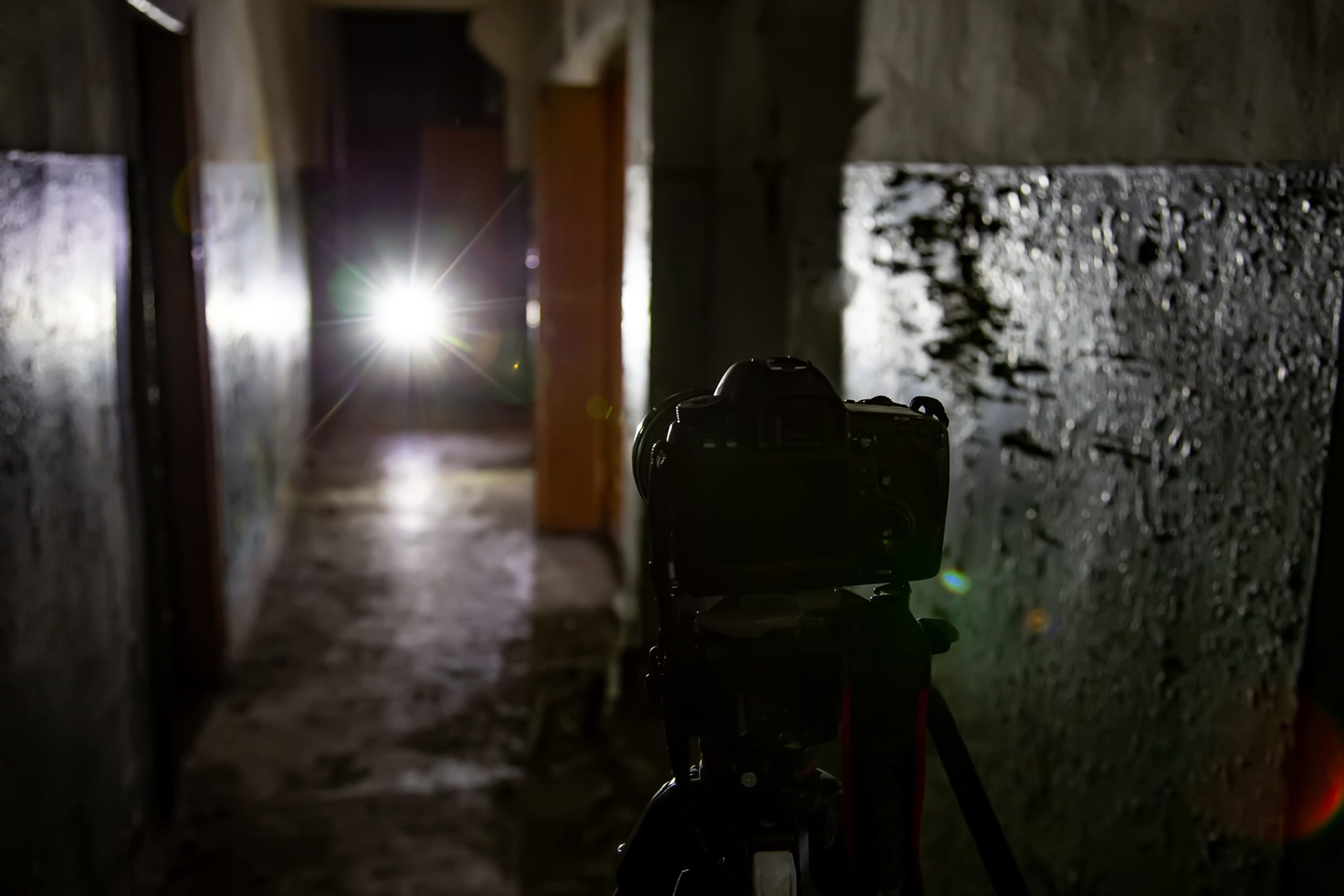 Camera on tripod in dark abandoned building. Urban exploration concept.