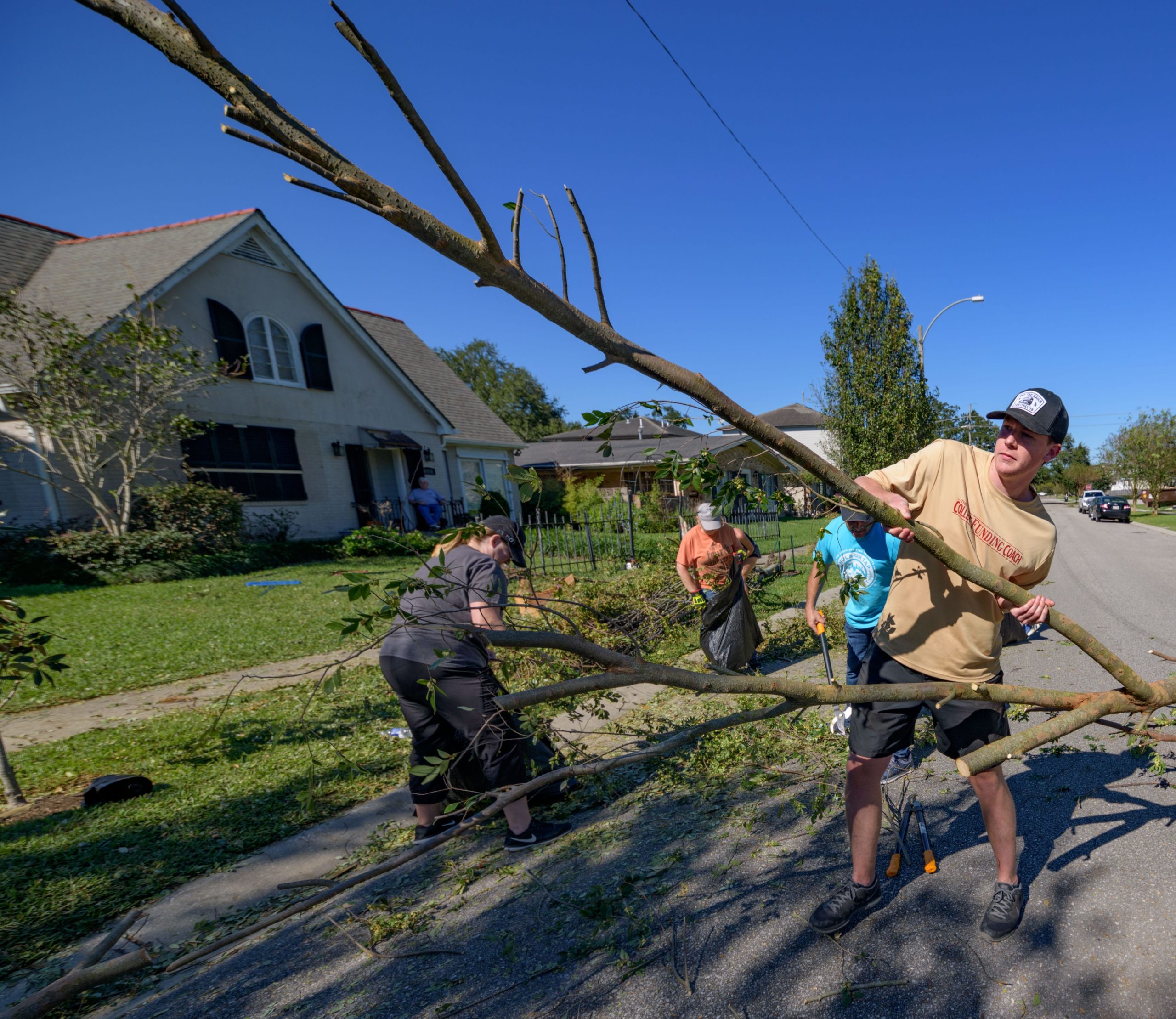 Lakeview neighbors of Bruce Baudier, sitting on porch, help remove a tree from in front of his home on Louis XIV street in New Orleans, Thursday, Oct. 29, 2020, after Hurricane Zeta passed through the city Wednesday night. Baudier said Lakeview really came together to help me out. Photo by Matthew Hinton