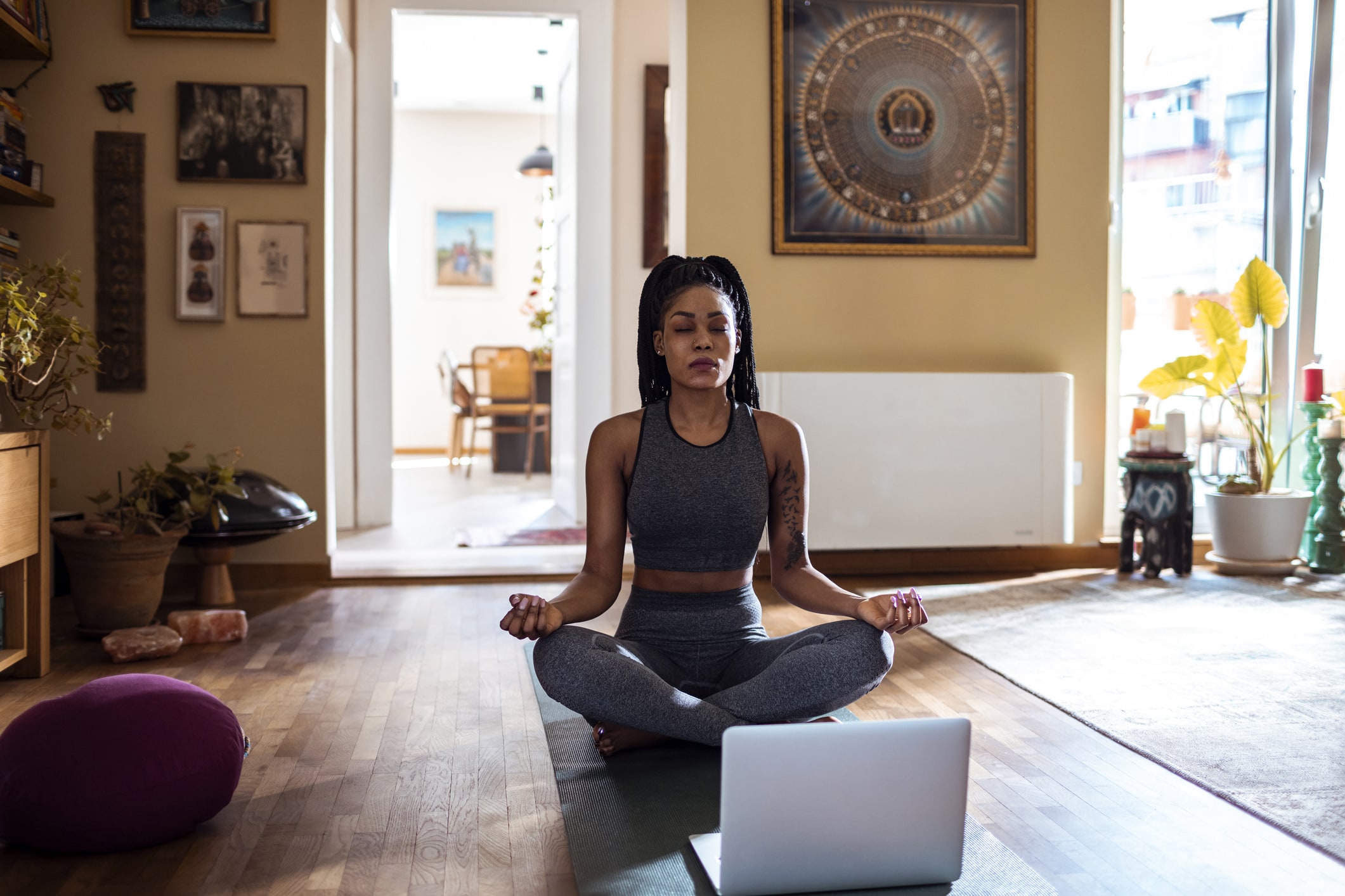 Close up of a young woman meditating at home and looking at instructions on the laptop