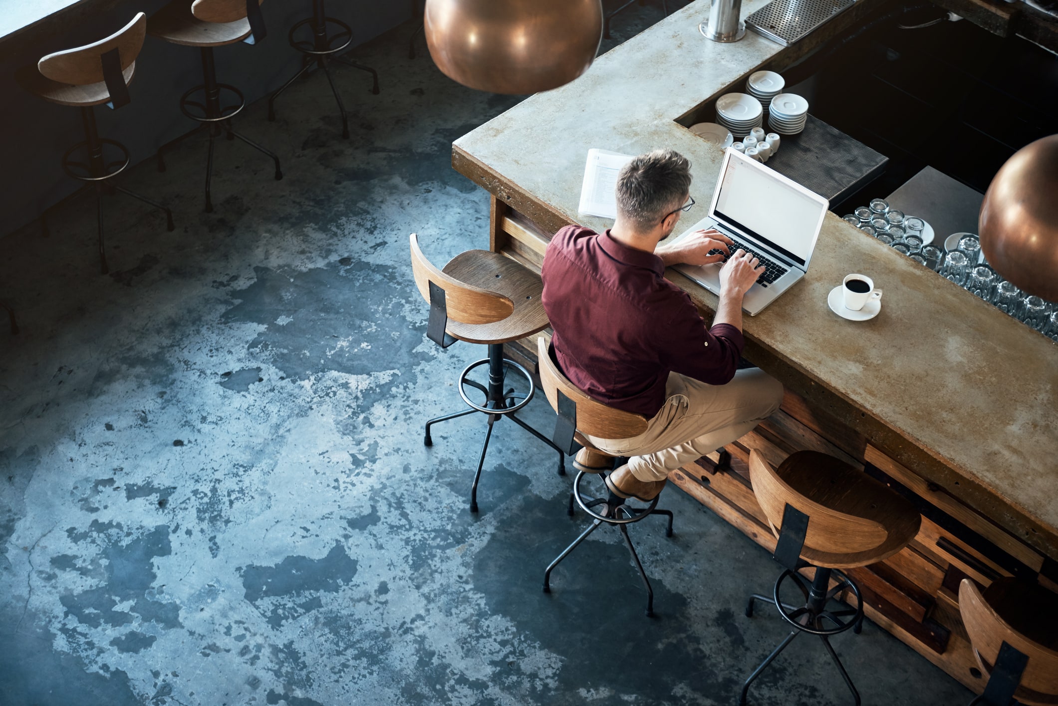 High angle shot of a businessman working on his laptop at the bar in a cafe