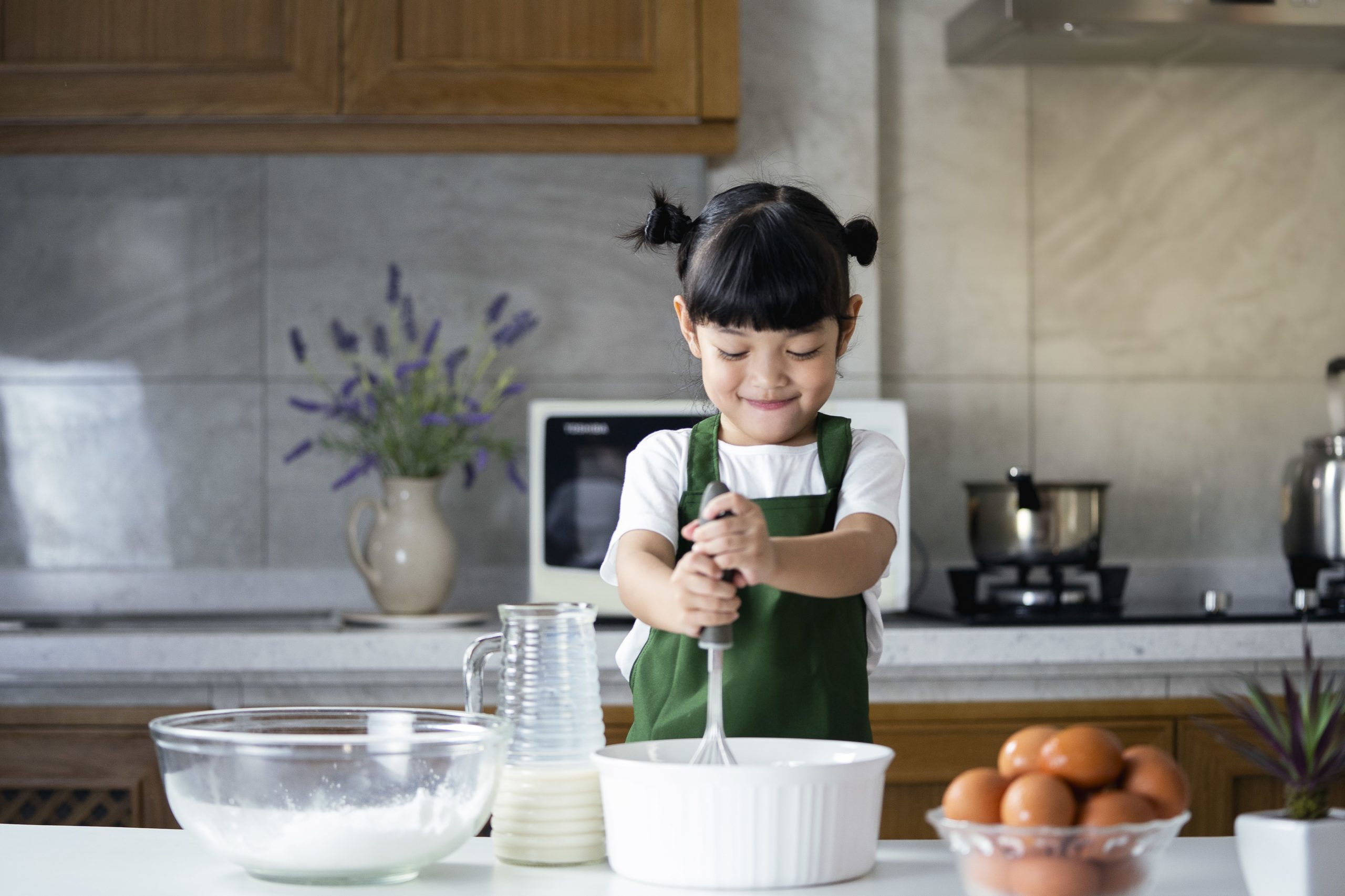 child girl enjoy cooking in the kitchen. Happy Asian kid is preparing the dough, bake cookies in the kitchen.