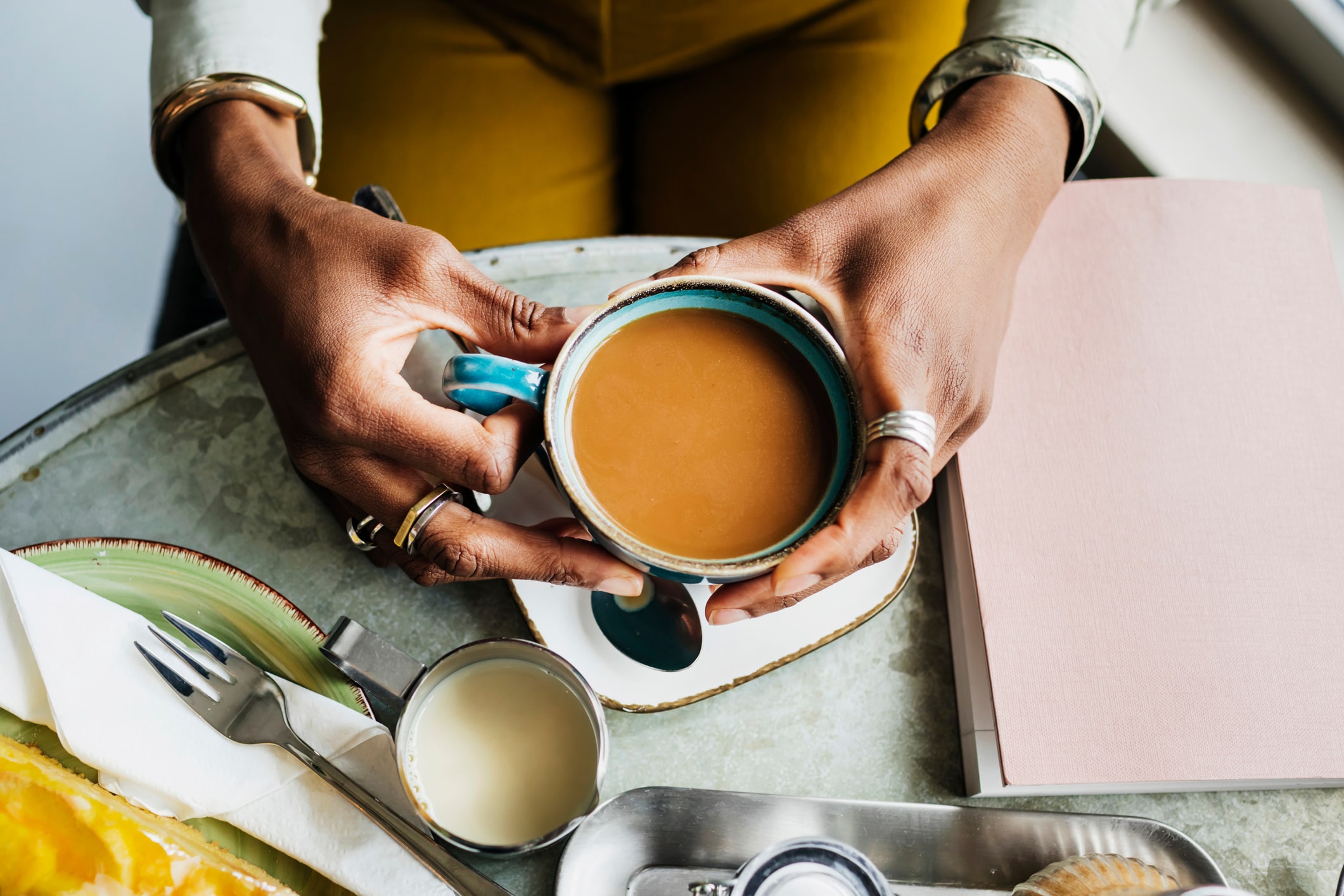 An aerial view of a woman drinking coffee while sitting at a table in a vegan cafe.