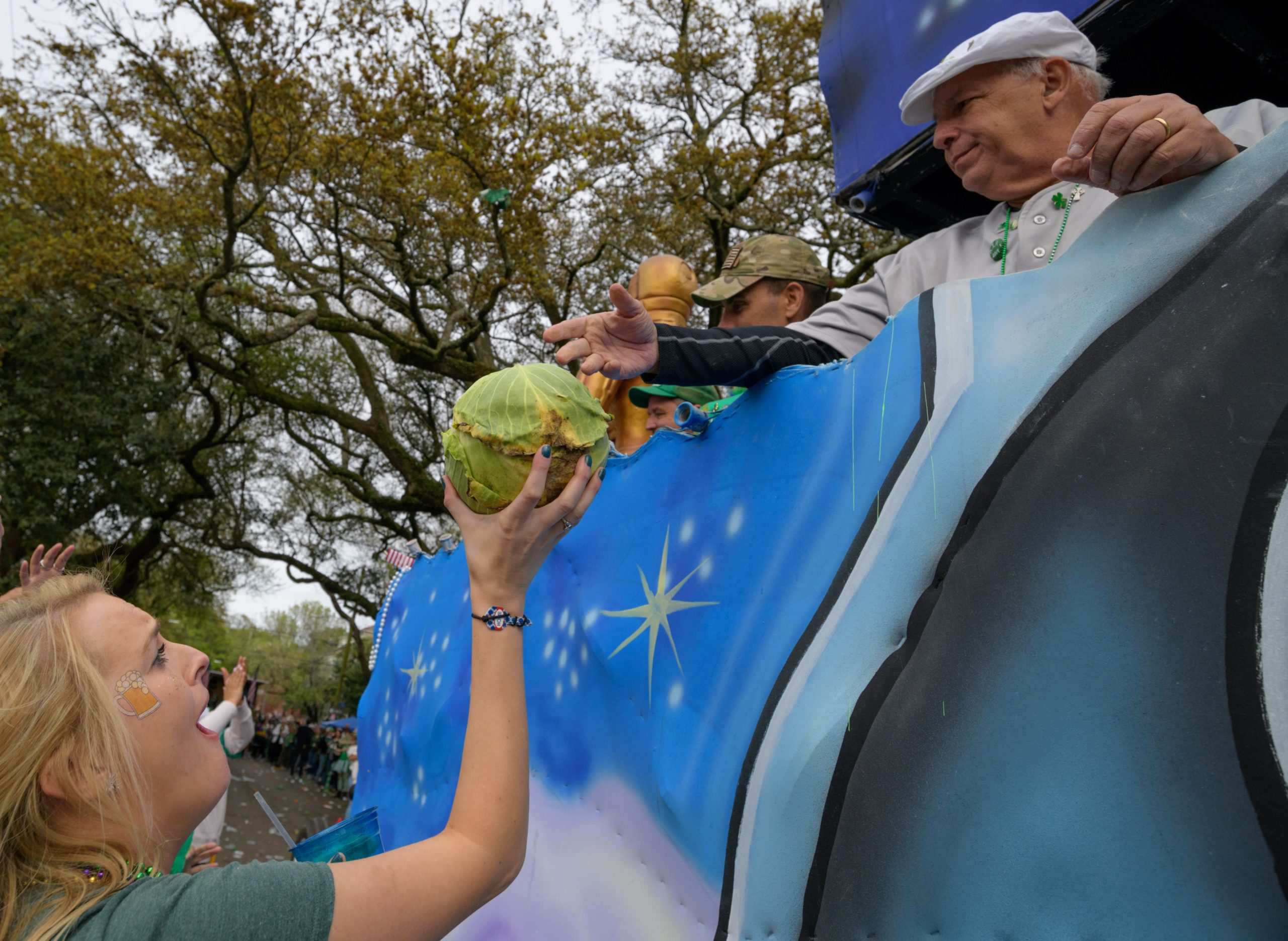 A float rider throws cabbage during the Irish Channel St. Patrick's Parade in New Orleans, La. Saturday, March 16, 2019. Cabbage is an ingredient of many traditional Irish dishes for St. Patrick's Day including corned beef and cabbage and it's the most coveted throw during the parade. Photo by Matthew Hinton