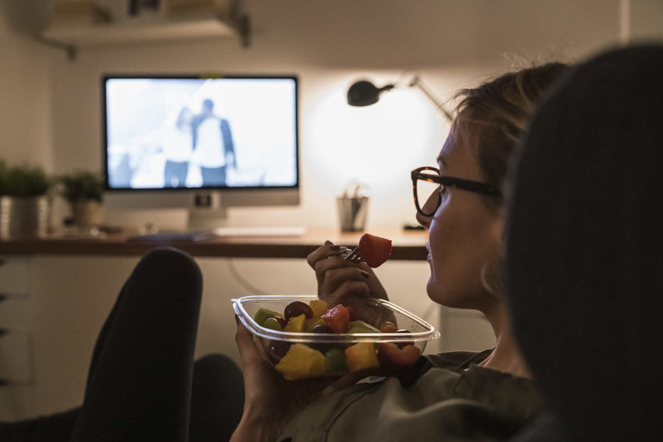 Woman relaxing in front of TV with fruit salad