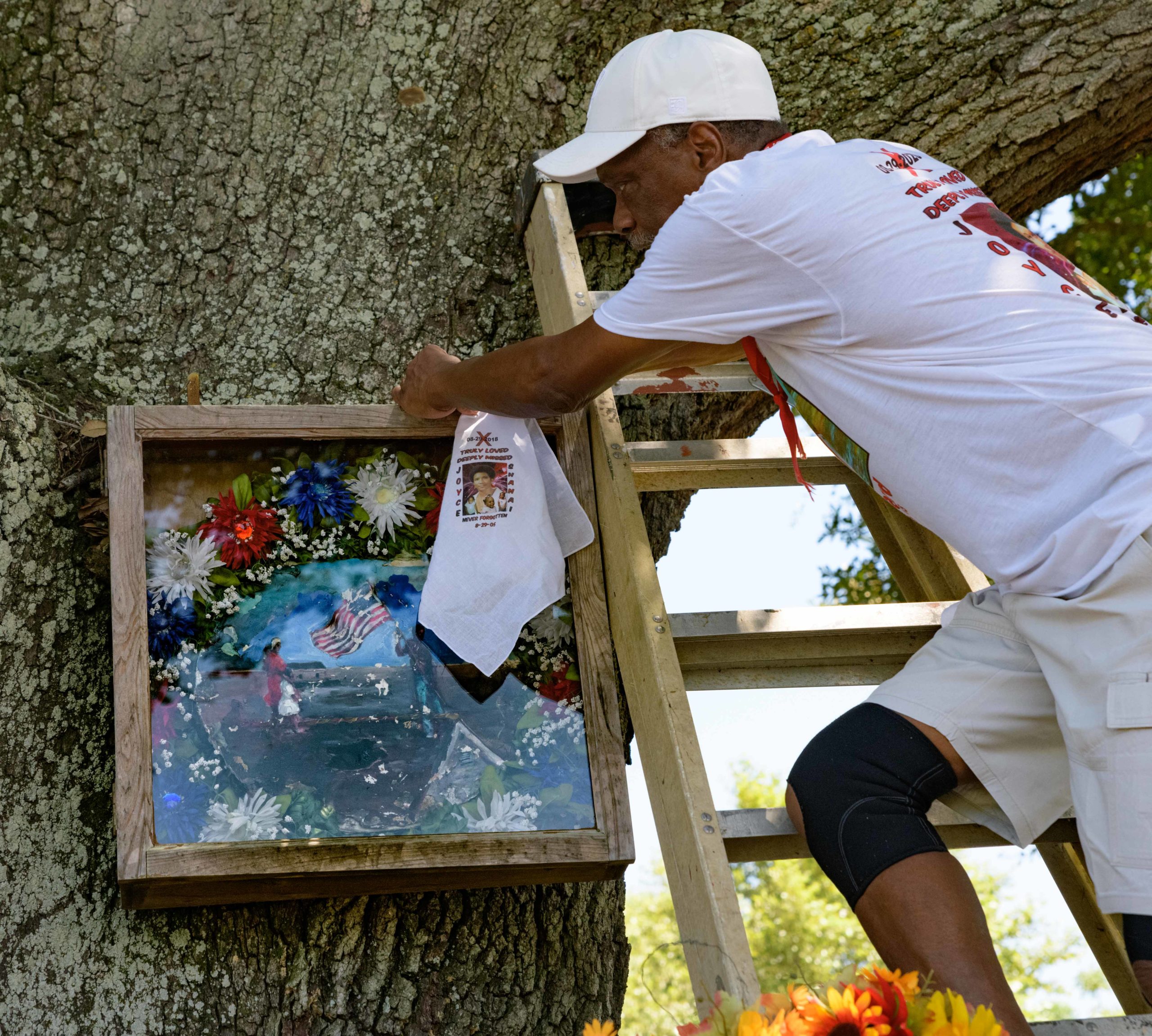 On Thursday, Aug. 29, 2019, Robert Green places a wreath in remembrance of his mother, Joyce, and granddaughter, Shanai, at the tree where his family home came off its foundation and floated down Tennessee Street in the Lower 9th Ward after the federal levee failures after Hurricane Katrina on August 29, 2005 in New Orleans. The family had to ride the roof and his mother and granddaughter did not survive the flood. Every year Green leads the Original Roof Top Riders second line to place a wreath on the anniversary of Katrina. This year the Da Truth Brass Band and Original Big Nine Social and Pleasure Club joined him and Big Chief Victor Harris, Spirit of the FiYiYi, of the Mandingo Warriors Mardi Gras Indians. Green was one of the first residents to return to the Lower 9th Ward and his home was replaced by actor Brad Pitt’s Make It Right Foundation. Photo by Matthew Hinton