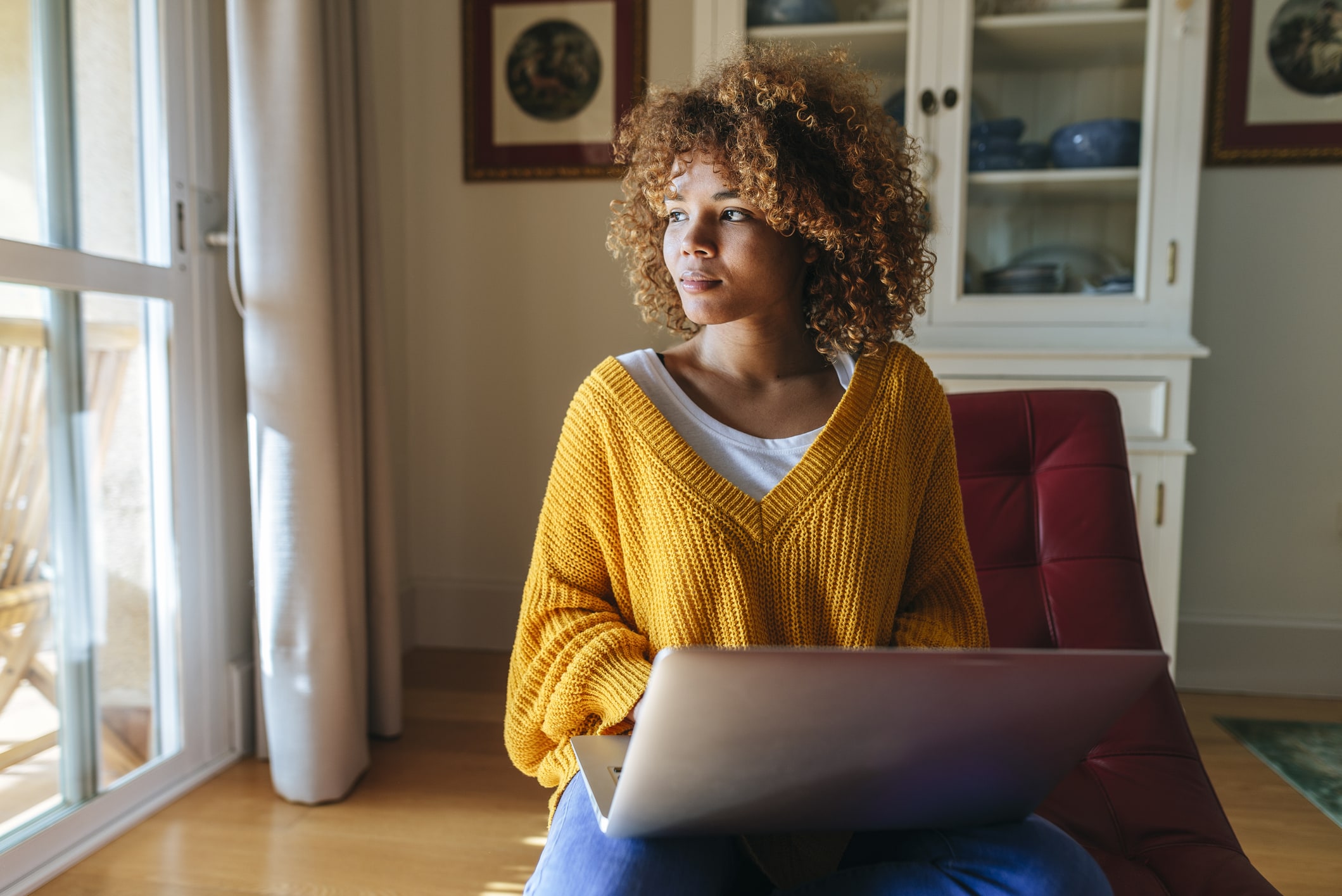 Young woman sitting on chaiselongue using laptop at home