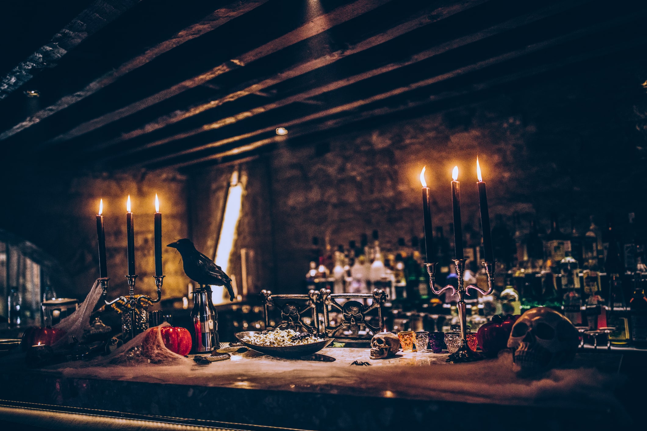 Spooky Halloween themed decoration with candles and skulls on nightclub bar counter for scary party