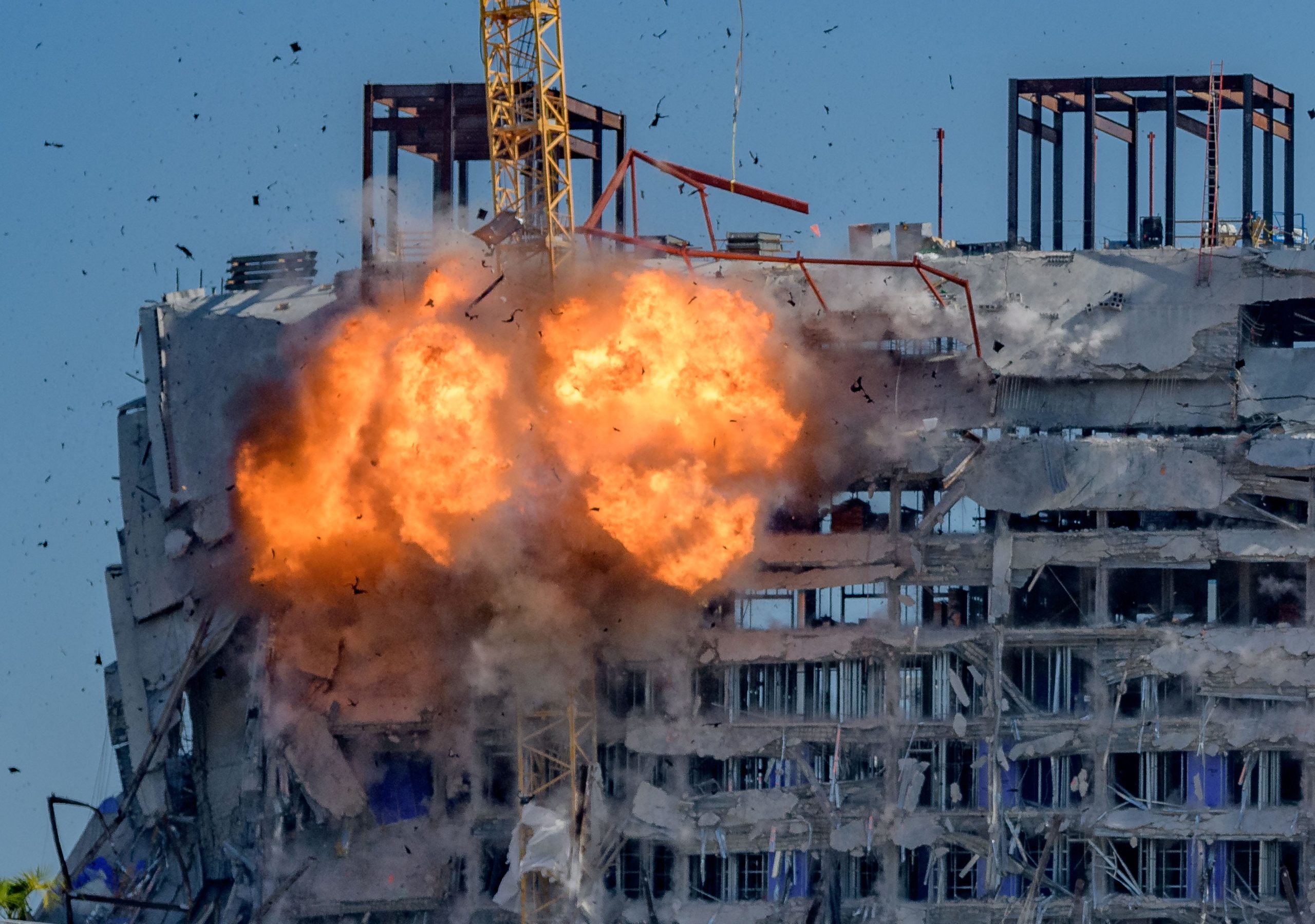 Two cranes begin to come down after a demolition implosion at the Hard Rock Hotel collapse site in New Orleans Sunday October 20, 2019. Three people died and at least 20 were injured in the initial collapse on Saturday October 12th. No one was injured Sunday when the demolition caused one of the two cranes to land in the street below. A sewer line was damaged but the buried gas and electrical lines were not damaged according to city officials. The historical Saenger Theatre did not sustain major damage at the crane collapse with the crane just missing the theater. The crane was already leaning after the initial collapse and would have likely fallen down in the next few days without a planned demolition. Photo by Matthew Hinton