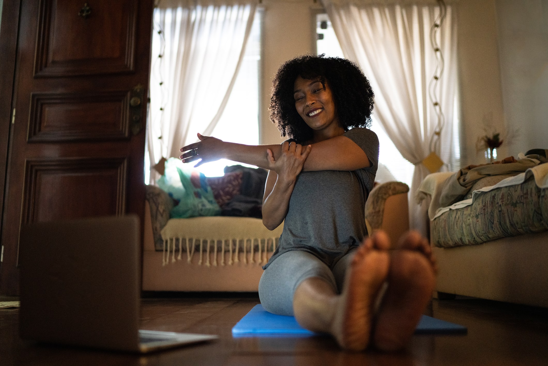 Woman watching gym class on laptop and doing exercises at home