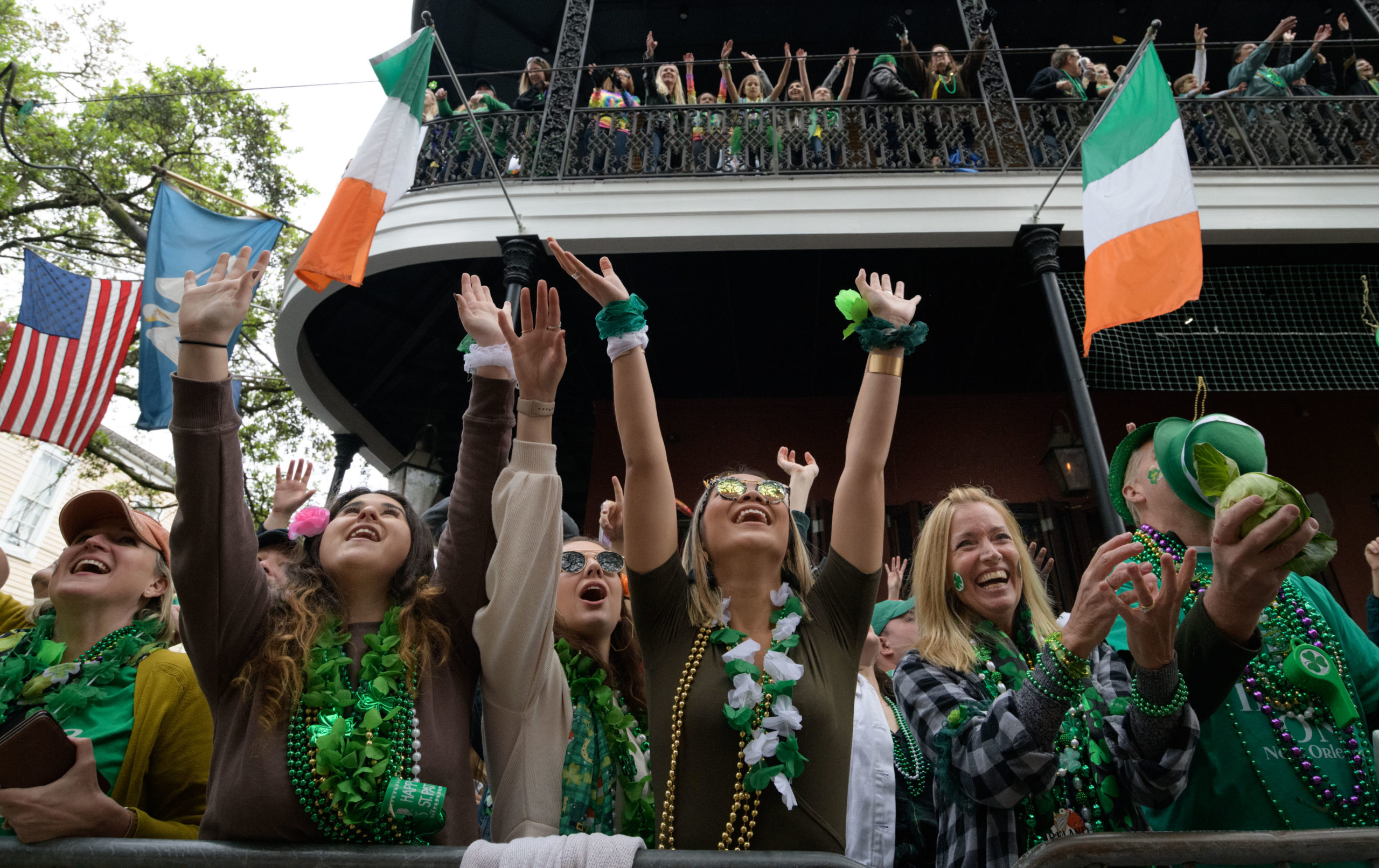Crowds beg for beads and cabbage from both stories of Tracey's Original Irish Channel Bar, which is celebrating its 70th anniversary, during the Irish Channel St. Patrick's Parade in New Orleans, La. Saturday, March 16, 2019. Photo by Matthew Hinton