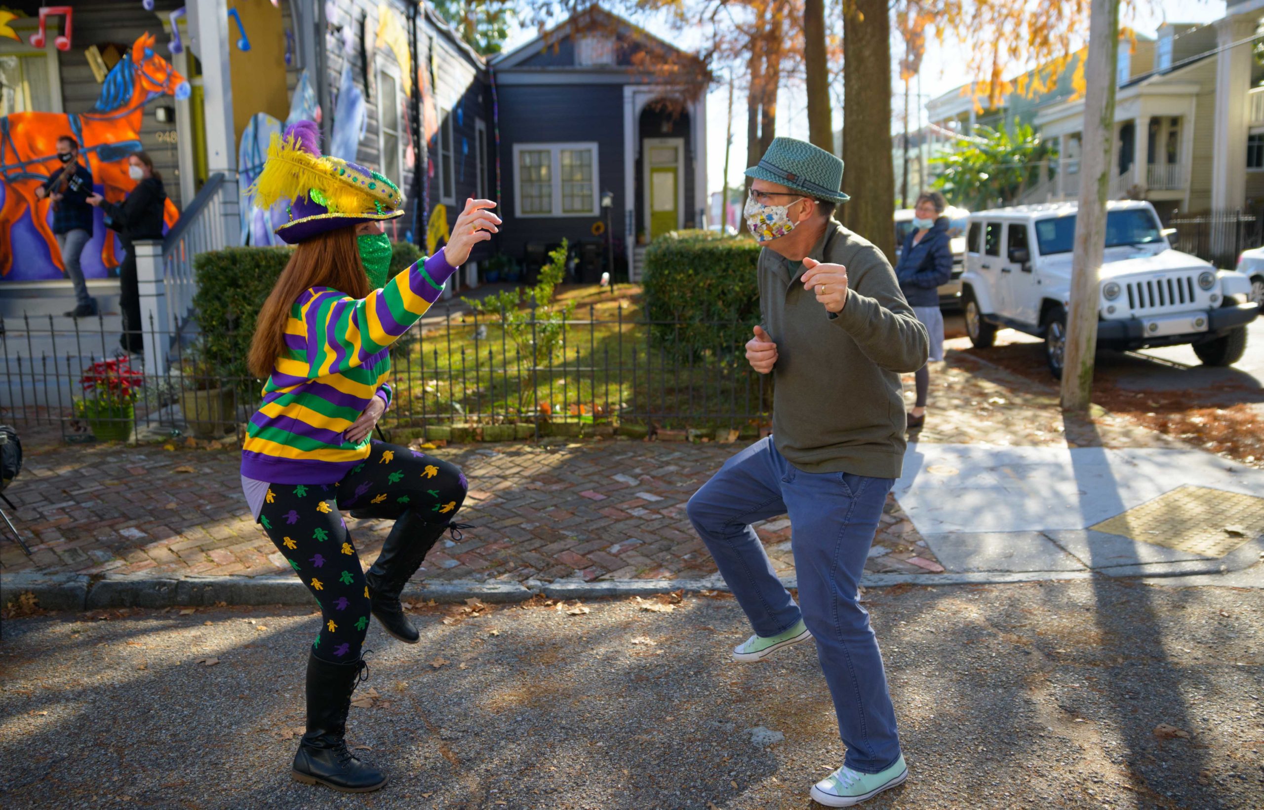 Michael and Stacey Burke to a three-piece Cajun band led by fiddler-singer Louis Michot of the Lost Bayou Ramblers in front of the Acadiana Hayride house float by Hire A Mardi Gras Artist, a grassroots initiative by the Krewe of Red Beans. The float features a horse-drawn hayride of Zydeco and Cajun music legends like Wilson Anthony "Boozoo" Chavis, D.L. Menard, and Clifton Chenier. A giant accordion that would take at least two people to play was put on the top of the home and was installed by Travis Keene, black jeans, and Joey Mercer, blue jeans, with a little help from Michael Burke. Burke is a retired gaffer or chief lighting technician for Law and Order SVU and Criminal Intent and he put his experience to work by lighting up the home at night.  The float wraps around to the other side with more notes and names of Cajun and Zydeco bands on the home on Euterpe Street in the Lower Garden District of New Orleans. The house float initiative hopes to build 40 house floats for every $15,000 donated. The donations go towards supplies and hiring float artists, many who are out-of-work because of the cancellation of Mardi Gras and Carnival parades due to the COVID-19 pandemic. Residents who live and own a home in Orleans Parish that donate to the project are entered into the raffle to get one of the house floats even for a small sum like $25. The #HouseFloat was designed by Caroline Thomas with additional artwork by Ryan Blackwood and Daniel Fuselier. Photo by Matthew Hinton