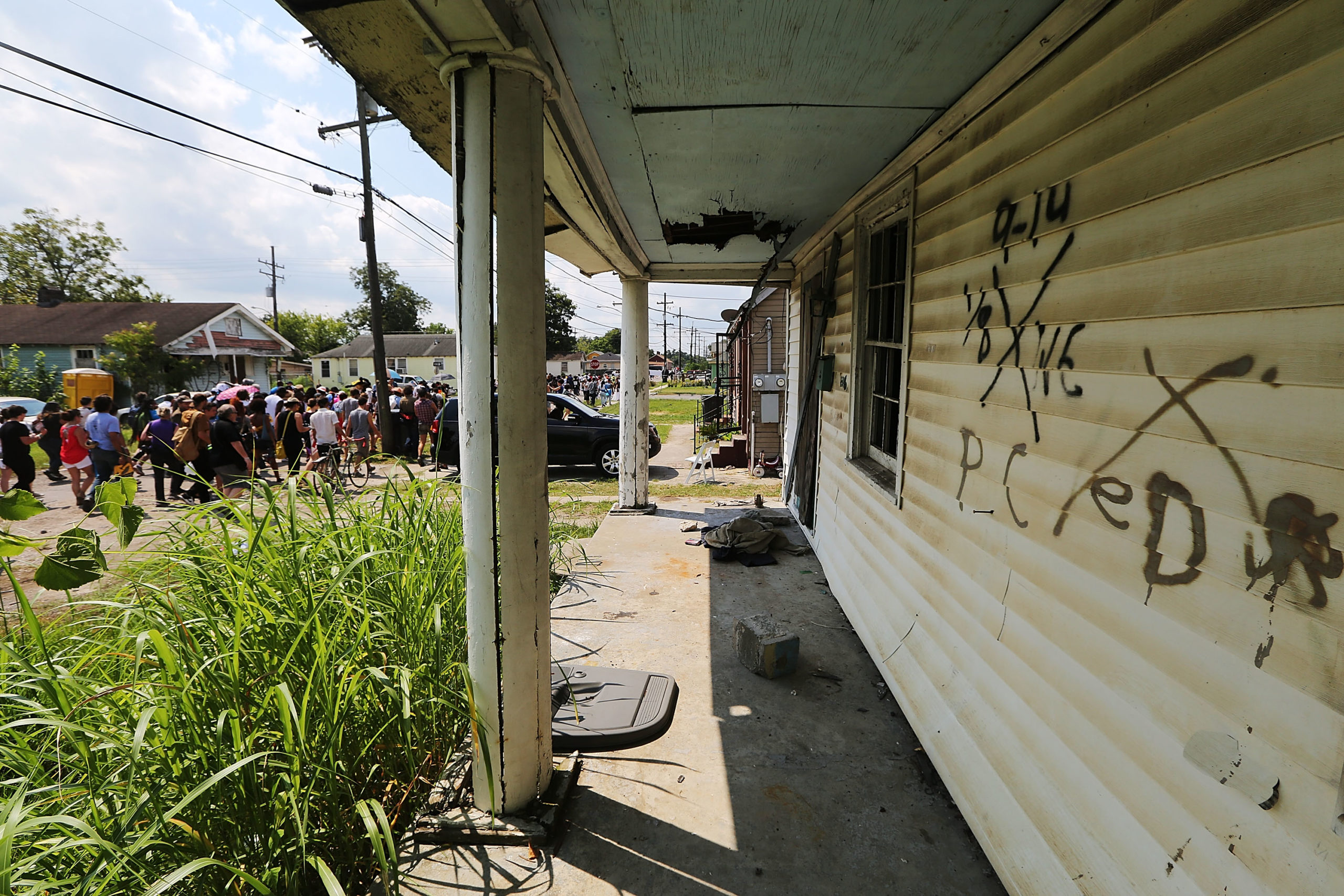 NEW ORLEANS, LA - AUGUST 29:  Revelers march past an abandoned home still marked by rescue markings in the Lower Ninth Ward during a second line parade marking the 10th anniversary of Hurricane Katrina on August 29, 2015 in New Orleans, Louisiana.  A levee breach along the Industrial Canal in the Lower Ninth Ward devastated the area with massive flooding in the aftermath of Hurricane Katrina.  (Photo by Mario Tama/Getty Images)