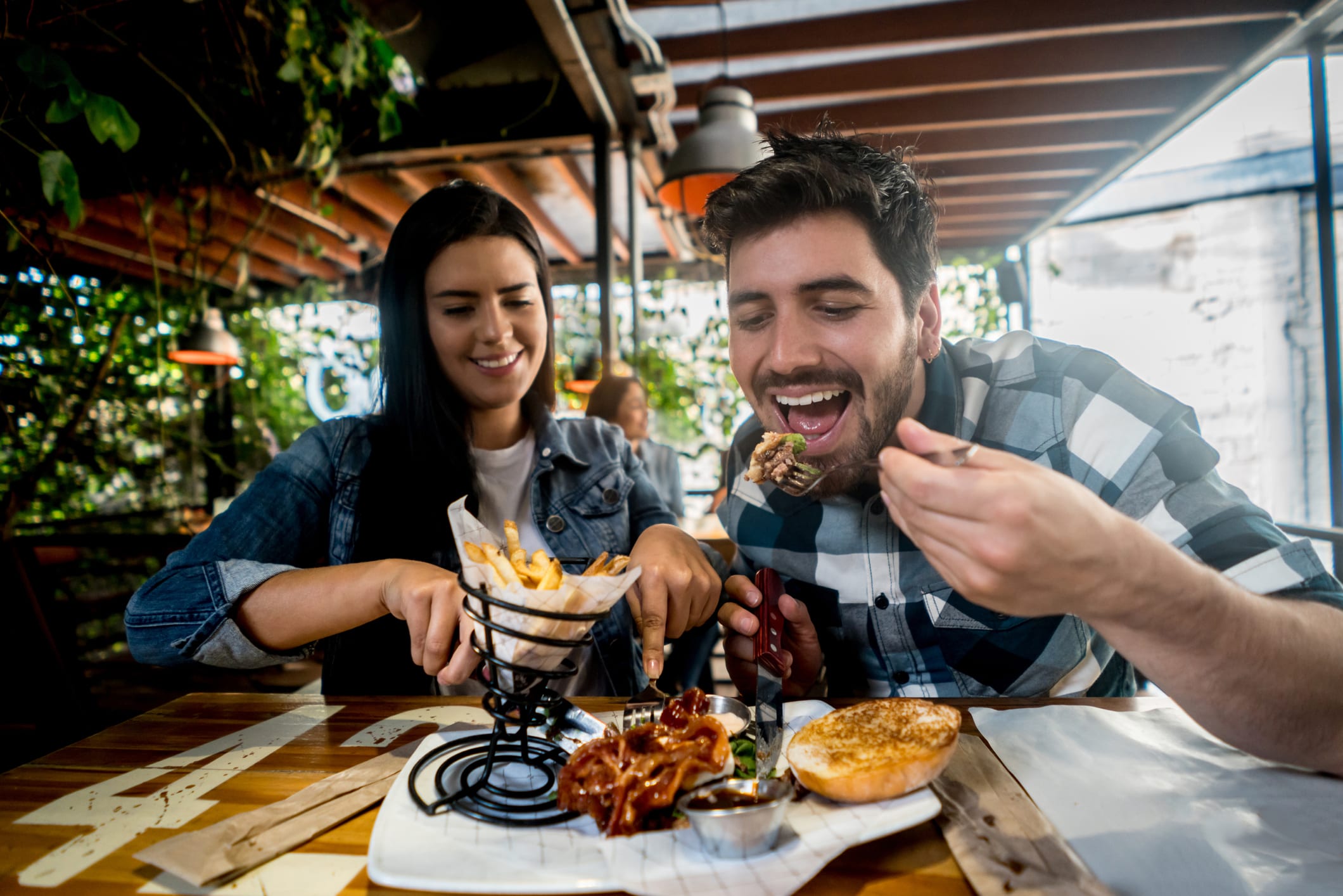 Loving couple eating together at a burgerâs restaurant and looking happy on a date