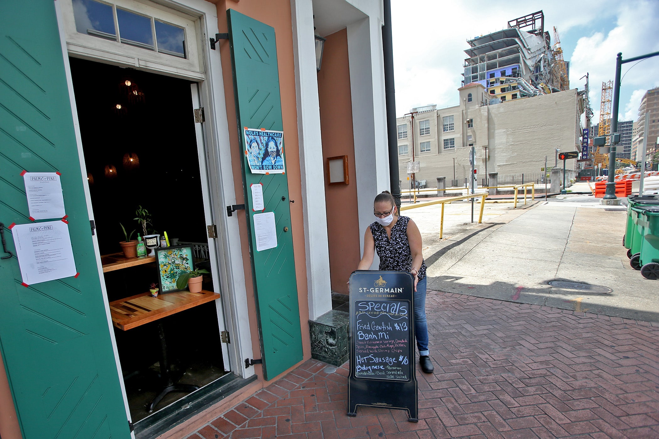 Monica Snoddy puts out a daily specials board at the Palm &amp; Pine restaurant on North Rampart Street near the collapsed Hard Rock Hotel on Saturday, May 23, 2020. (Photo by Michael DeMocker)