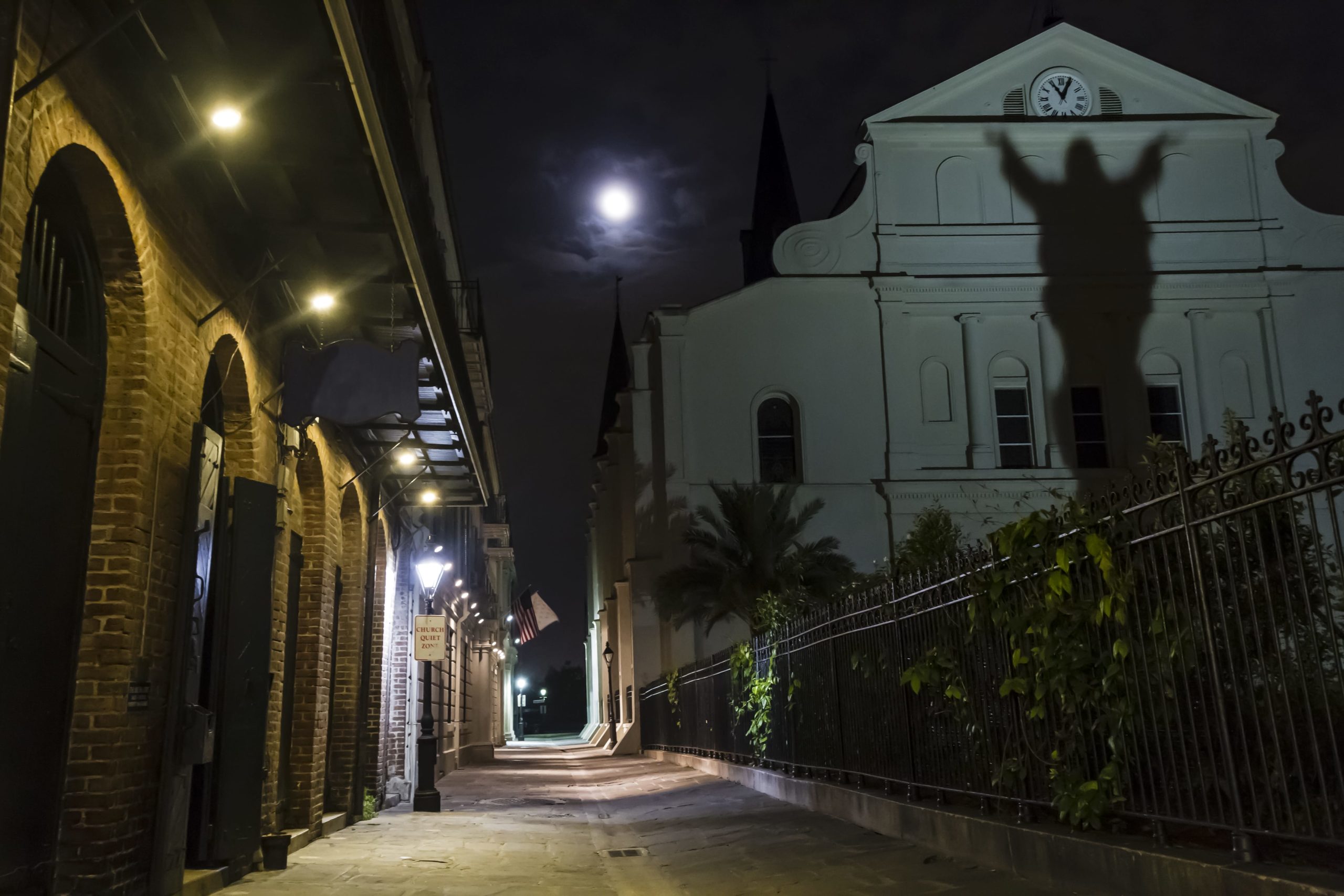 A full moon rises over Pere Antoine Alley and St. Anthony's Garden with a shadow on the rear of St. Louis Cathedral in the French Quarter of New Orleans, Louisiana.