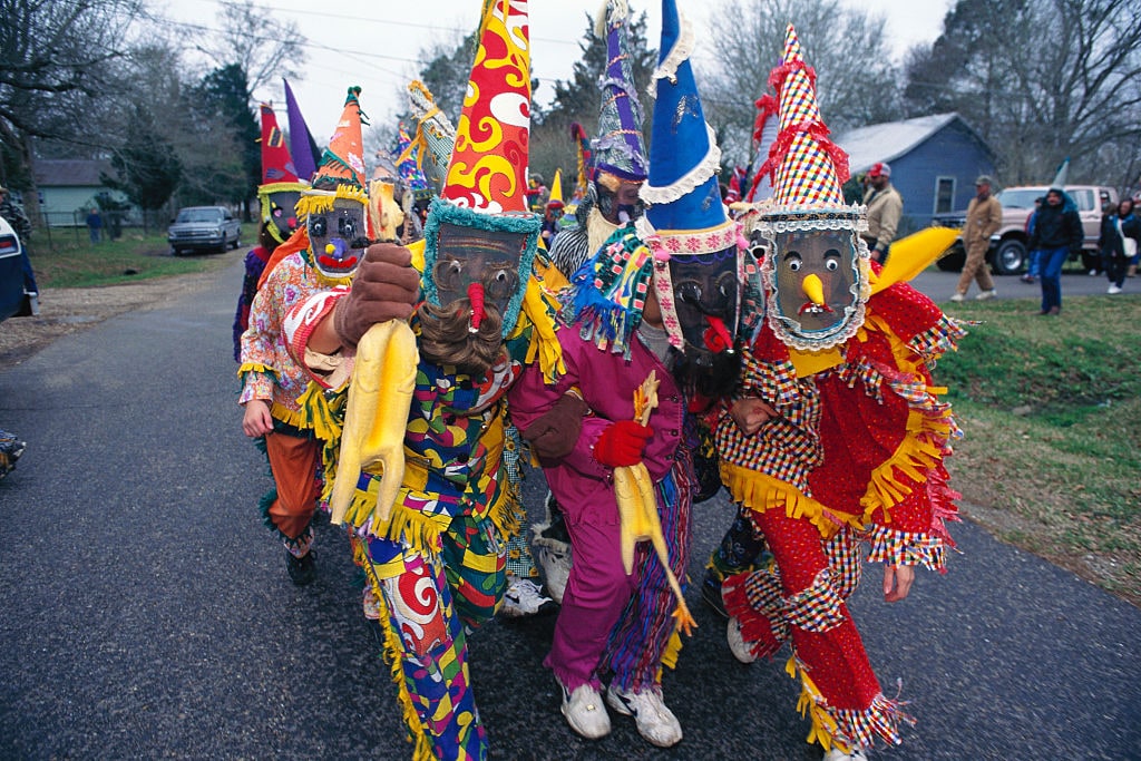 (Original Caption) Louisiana: Each year at Mardi Gras time, rowdy parades roll and revelers fight over worthless trinkets, an equally crazed celebration unfolds in the Cajun and Creole country 150 miles to the west. Hundreds of horseback riders dressed in medieval mummers costumes and masks gather for the purpose of chasing chickens. This is rural Mardi Gras, a pre-Lenten celebration from medieval Europe. As they have for generations for four days before Ash Wednesday, the celebrant go about collecting ingredients for a group gumbo, seeking "charity" - a dominion of rice, sausage, onions - or a chicken. If a chicken is offered it is not simply handed over, but tossed into flight and then frantically followed over fences, through fields and streams until it is caught by hand. While the poultry is being pursued, the other costumed characters dance, gulp beer and generally cut up. The (Photo by mark peterson/Corbis via Getty Images)