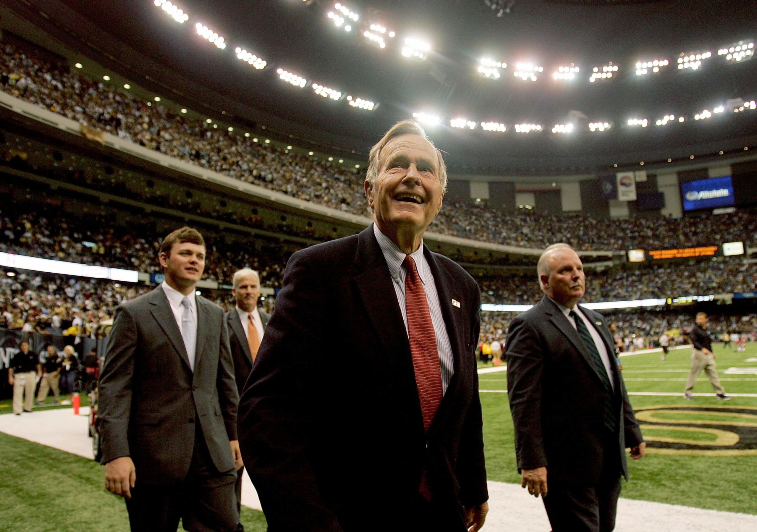 NEW ORLEANS - SEPTEMBER 25:  Former President of the United States, George H. W. Bush (C) walks on the field for the coin toss prior to the Monday Night Football game between the Atlanta Falcons and the New Orleans Saints on September 25, 2006 at the Superdome in New Orleans, Louisiana. Tonight's game marks the first time since Hurricane Katrina struck last August, that the Superdome, which served as a temporary shelter to thousands of stranded victims in the wake of Katrina, has played host to an NFL game.  (Photo by Ronald Martinez/Getty Images)