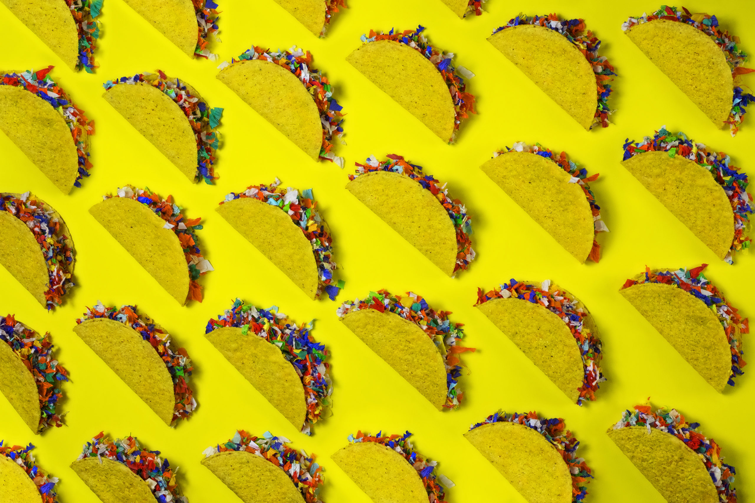 Rows of taco shells stuffed with colorful confetti - taco party concept