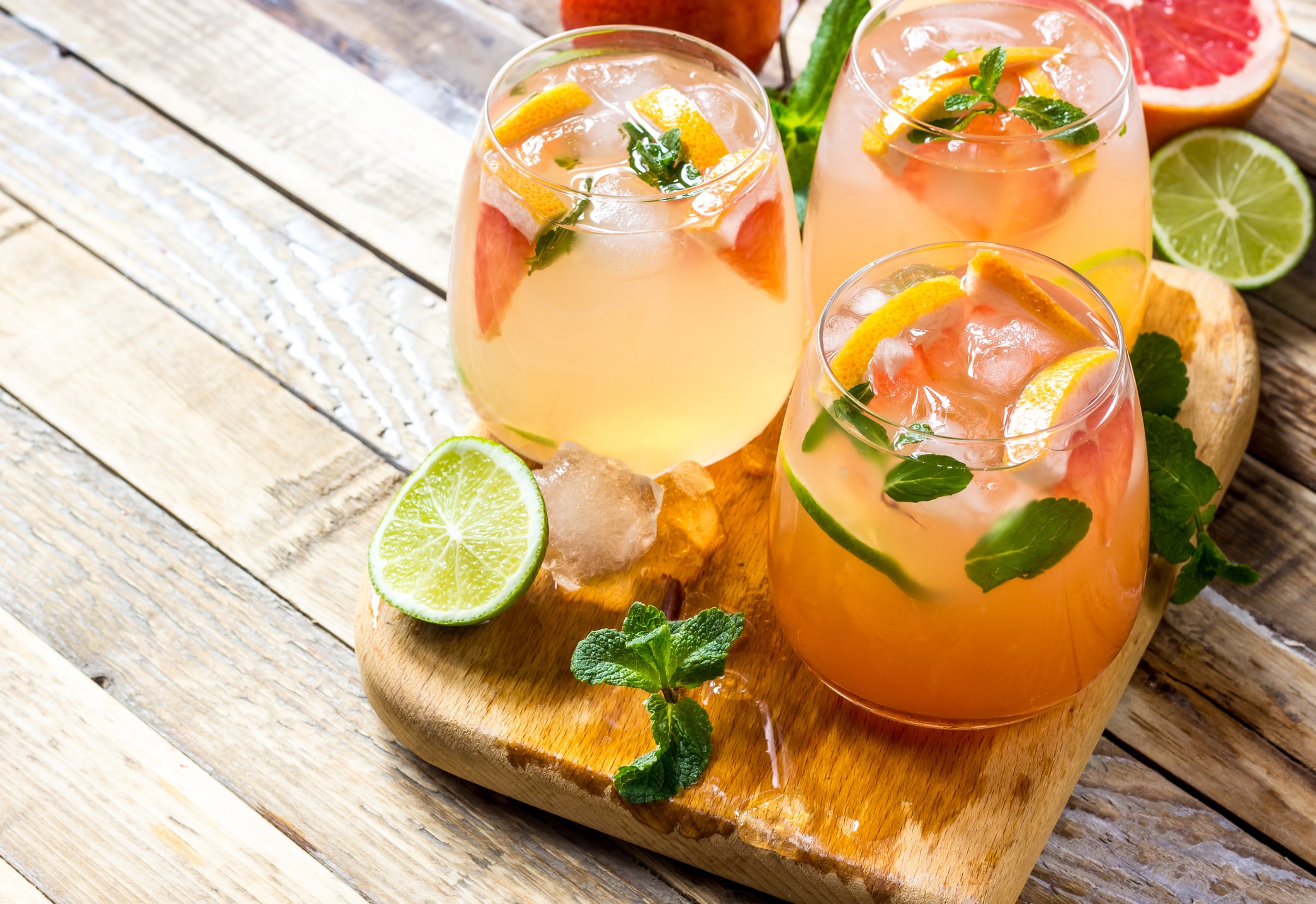 Grapefruit and mint gin cocktail, refreshing drink with ice on wooden background. Selective focus