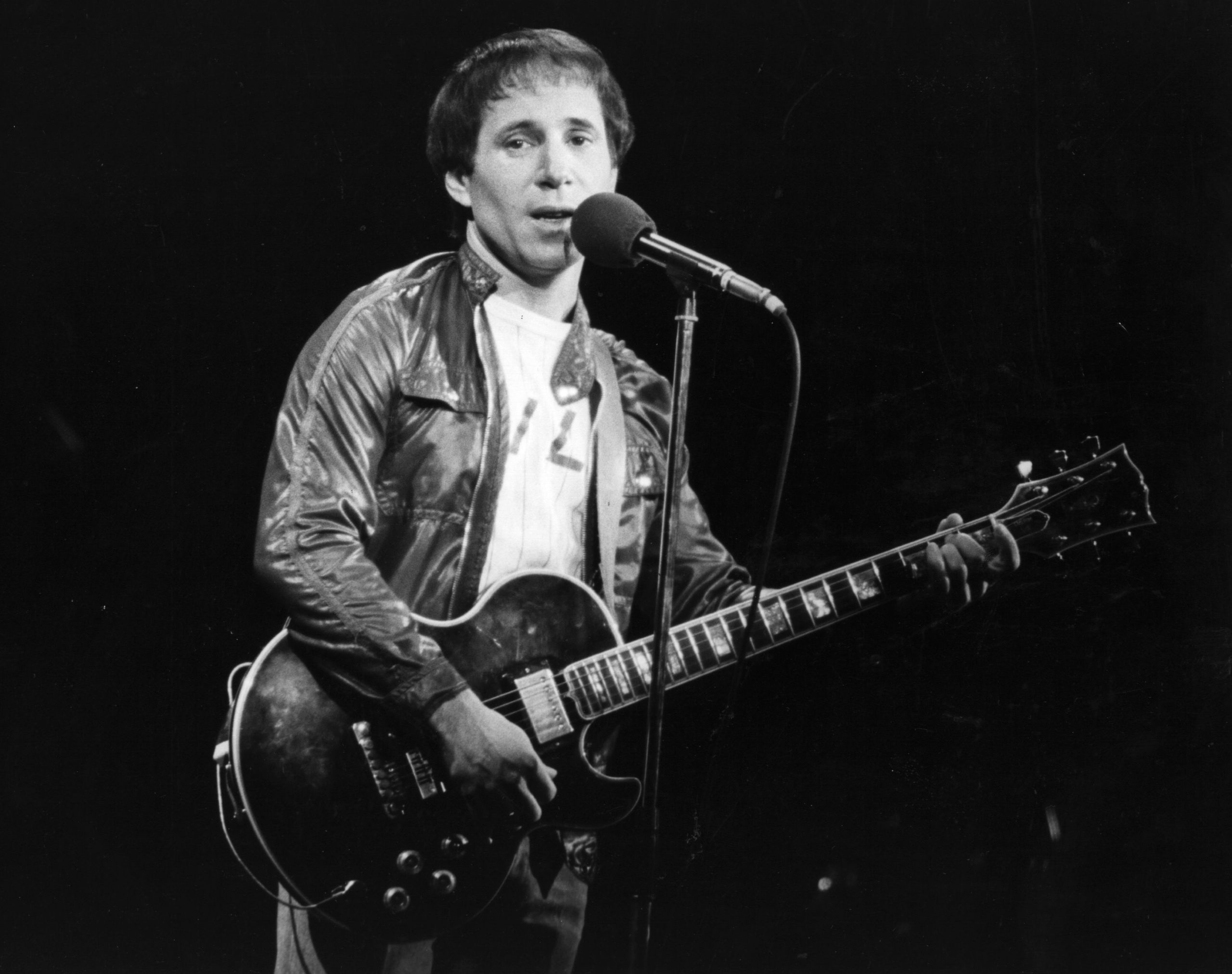 circa 1980:  American pop singer and songwriter Paul Simon performing in London, during a series of solo concerts with a backing band and chorus. During the previous four years he was involved in a film, 'One Trick Pony', which he wrote and starred in. He now lives with actress Carrie Fisher, whilst his eight year old son Harper lives nearby in New York with Paul's ex-wife Peggy.  (Photo by Keystone/Getty Images)